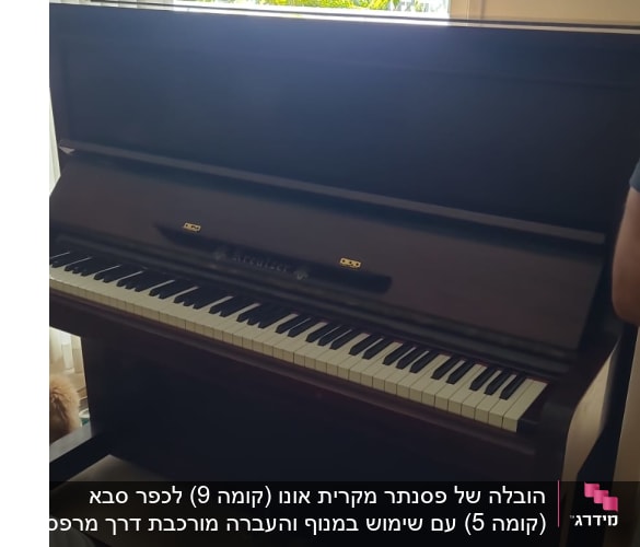 פסנתר עומד ליד חלון עם וילון פתוח